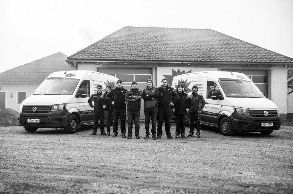 Acht Personen zwischen zwei CHIP Elektrotechnik Transportern vor Werkhalle, Logos und Webadresse auf Fahrzeugen sichtbar